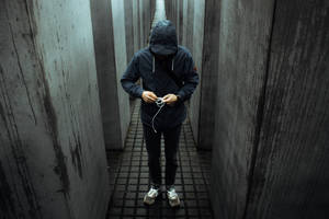 穿著深色連帽衫的人站在混凝土走廊裡拿著耳塞