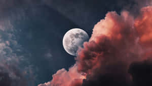 滿月在夜間多彩雲層後升起。