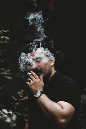 男人在黑暗森林中吸煙，煙霧在他臉龐周圍旋轉。
