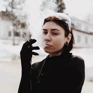 戴黑色手套的女性在雪景都市環境中戶外吸煙。