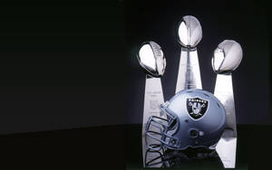 黑色背景上嘅Raiders頭盔同三個超級碗獎盃