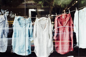 衣服掛在商店櫥窗內的繩子上，帶有倒影。