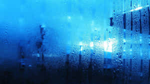 帶有藍色調的窗戶，有雨滴和夜間外面模糊的燈光。 — 雨天 壁紙