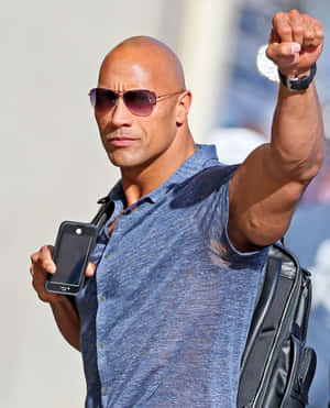Dwayne Johnson 戴住太陽眼鏡拎住電話同舉起拳頭。 — Galaxy Z Fold 5 壁紙
