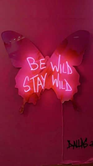 粉紅色霓虹燈蝴蝶標誌，在粉紅色牆壁上帶有塗鴉，寫着「Be Wild Stay Wild」。