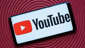 智能手機在紅色螺旋背景上顯示 YouTube 應用程式標誌。 — YouTube 壁紙