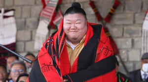 身穿傳統紅黑長袍的相撲選手在活動中微笑