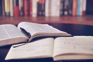 打開的字典和筆記本，筆放在書架附近的桌子上。