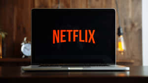 手提電腦在木桌上顯示Netflix標誌，帶有溫暖的燈光。