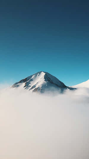 在蔚藍天空下，白雪覆蓋的山峰從雲層中浮現