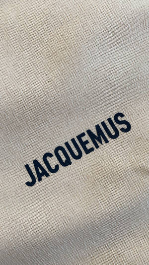 米色布料上以粗體刺繡的海軍藍 JACQUEMUS 標誌。