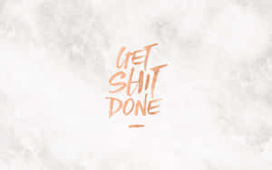 激勵語句 get shit done 以銅色畫筆字體寫喺有紋理嘅白色背景上。
