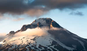 白雪覆蓋的山峰在日出光芒中閃耀，雲霧在山腳繚繞。 — 藍天 壁紙