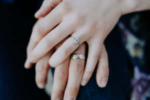 兩隻手交握，一隻有訂婚戒指，另一隻有結婚戒指