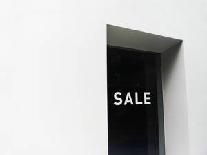 現代店舖的門，深色玻璃上以白色文字顯示減價標誌。