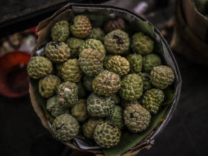 一個籃子裝滿了綠色釋迦果，放在香蕉葉上。 — 水果籃 壁紙