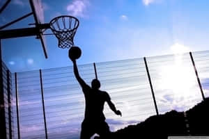 籃球運動員在明亮天空下入樽的剪影。