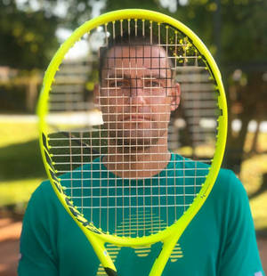 男子在戶外球場上將黃色網球拍舉在臉前。 — 網球 壁紙