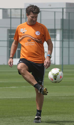 一名男足球員在訓練期間在草地上控制一個球。