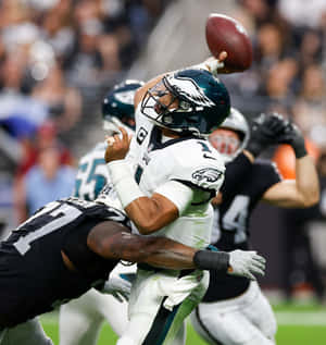 NFL四分衛在被防守球員擒抱時擲出橄欖球。 — Pixel 10 Pro Fold 壁紙