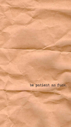 皺巴巴的棕色紙張，上面有黑色印刷的短語 be patient as fuck。