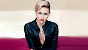 Miley Cyrus 身穿黑色皮褸，紅唇，坐在洋紅色沙發上