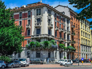 色彩繽紛的歷史公寓建築，設有陽台，汽車停放在陽光明媚的城市街道上。