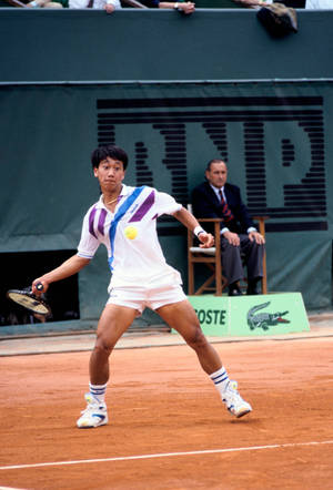 網球手在紅土場上擊球，背景有裁判。 — 網球 壁紙