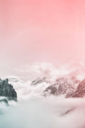 粉紅色的天空和雲朵飄過從霧中浮現的積雪群山。