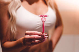 一位女性手持粉紅色剃刀。