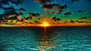 海面上鮮豔的夕陽，伴隨著多彩的雲朵和金色的水面倒影。