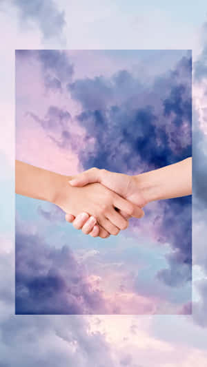 兩隻手在粉彩雲背景下握手。