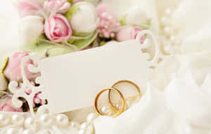 金色結婚戒指放在珍珠上，配以花朵和卡片，適合新娘主題。