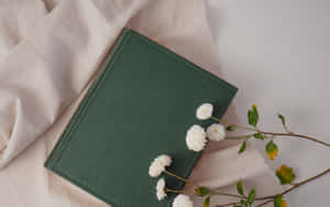 奶油色布料上的綠色書本與白色花朵