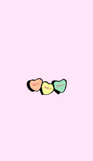 三粒彩色心形糖果，在粉紅色背景上寫著 truly madly deeply
