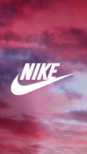 白色Nike標誌在粉紅和紫色日落天空前。 — iPhone 粉紅美學 壁紙