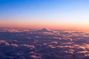 日出時山峰從雲層中浮現，天空呈現粉紅與藍色。