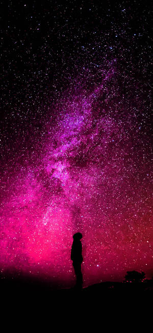 一個人站在粉紅色和紫色的星空下凝視著銀河。 — 銀河 壁紙