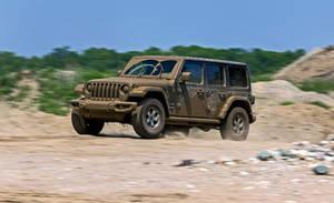 泥濘的Jeep Wrangler在岩石沙漠地形上高速行駛揚起灰塵。