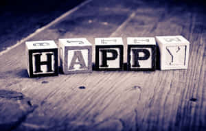 木塊在質樸的木質表面上拼出 happy。 — 友誼日 壁紙