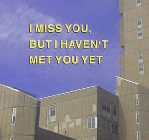 紫色天空和米色建築上方的黃色文字顯示 I MISS YOU BUT I HAVEN'T MET YOU YET — 傷感語錄 壁紙