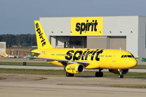 黃色Spirit Airlines飛機在機場跑道近機庫處。