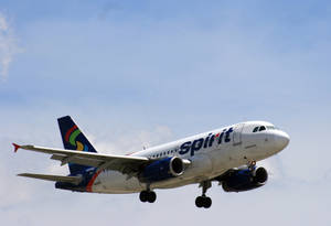 Spirit Airlines飛機在藍天下放下起落架降落。