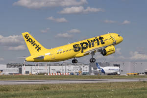 黃色Spirit Airlines噴射機從跑道爬升，背景為機場。