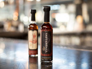 吧檯上兩瓶Tattersall Old Fashioned糖漿，背景有散景燈光。