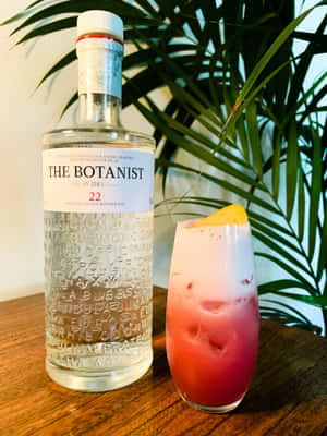 Botanist 氈酒瓶和粉紅色雞尾酒配檸檬，木桌上，棕櫚葉旁。