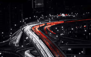 夜間高速公路交匯處，帶有紅色和白色車輛燈光的條紋。