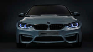 在黑暗的攝影棚中，銀色BMW M4的前視圖，帶有發光的藍色頭燈。 — 午夜 壁紙