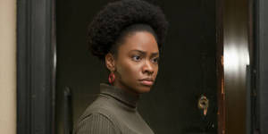 一位擁有非洲髮型和紅色耳環的女性在門口回頭看。 — 約翰·坎迪 GIF 壁紙