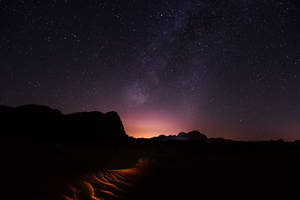沙漠沙丘上的繁星夜空，銀河和剪影岩石。